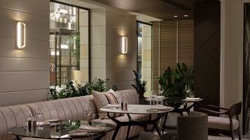 A modern dining area with a sofa, round tables, and chairs.