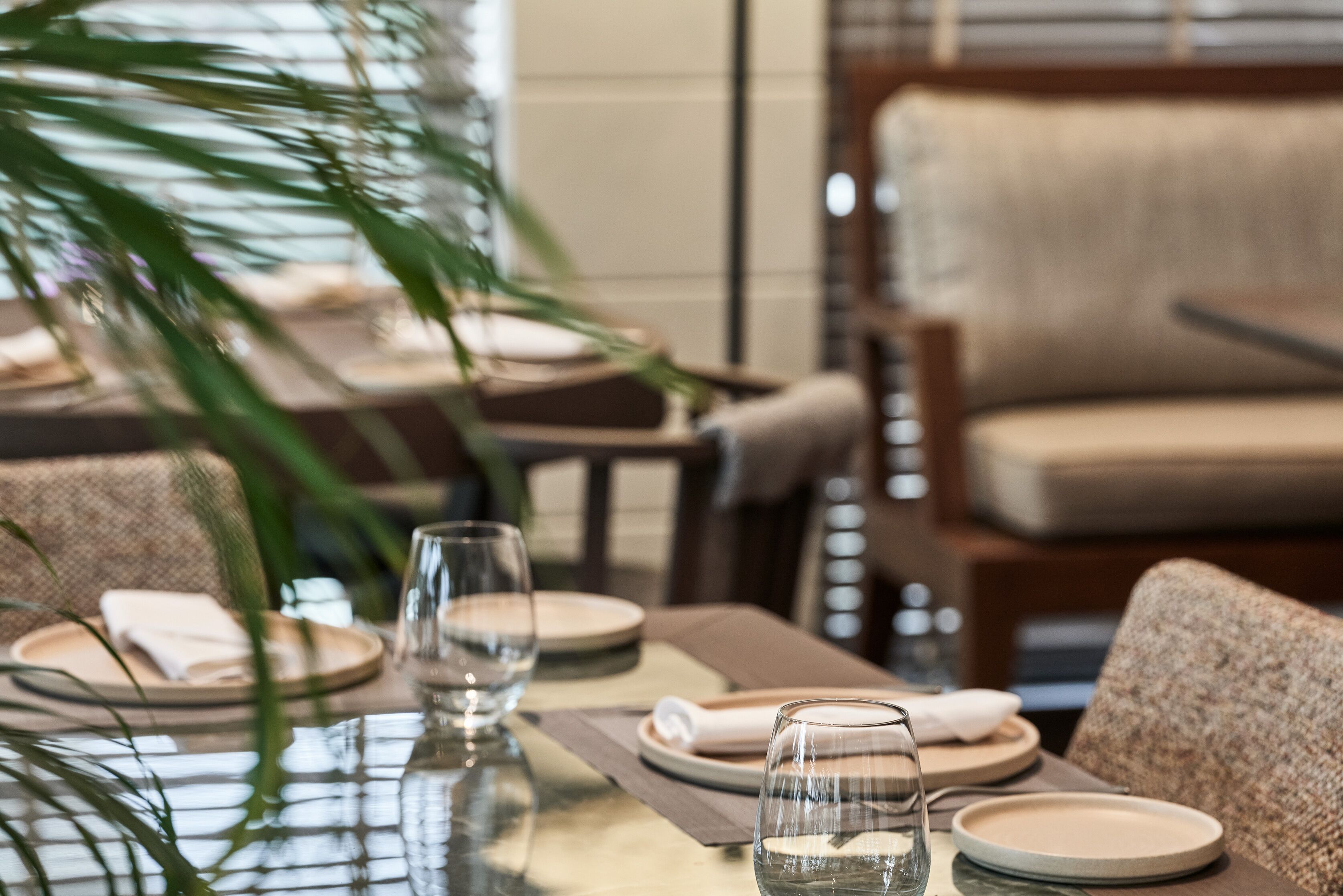 A dining table set with plates, glasses, and a napkin.