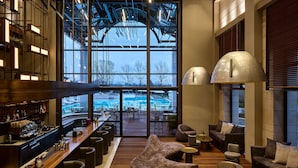 A modern bar area with a view of a pool through large windows. - September Hotel Thessaloniki (Pylaia-Chortiatis)