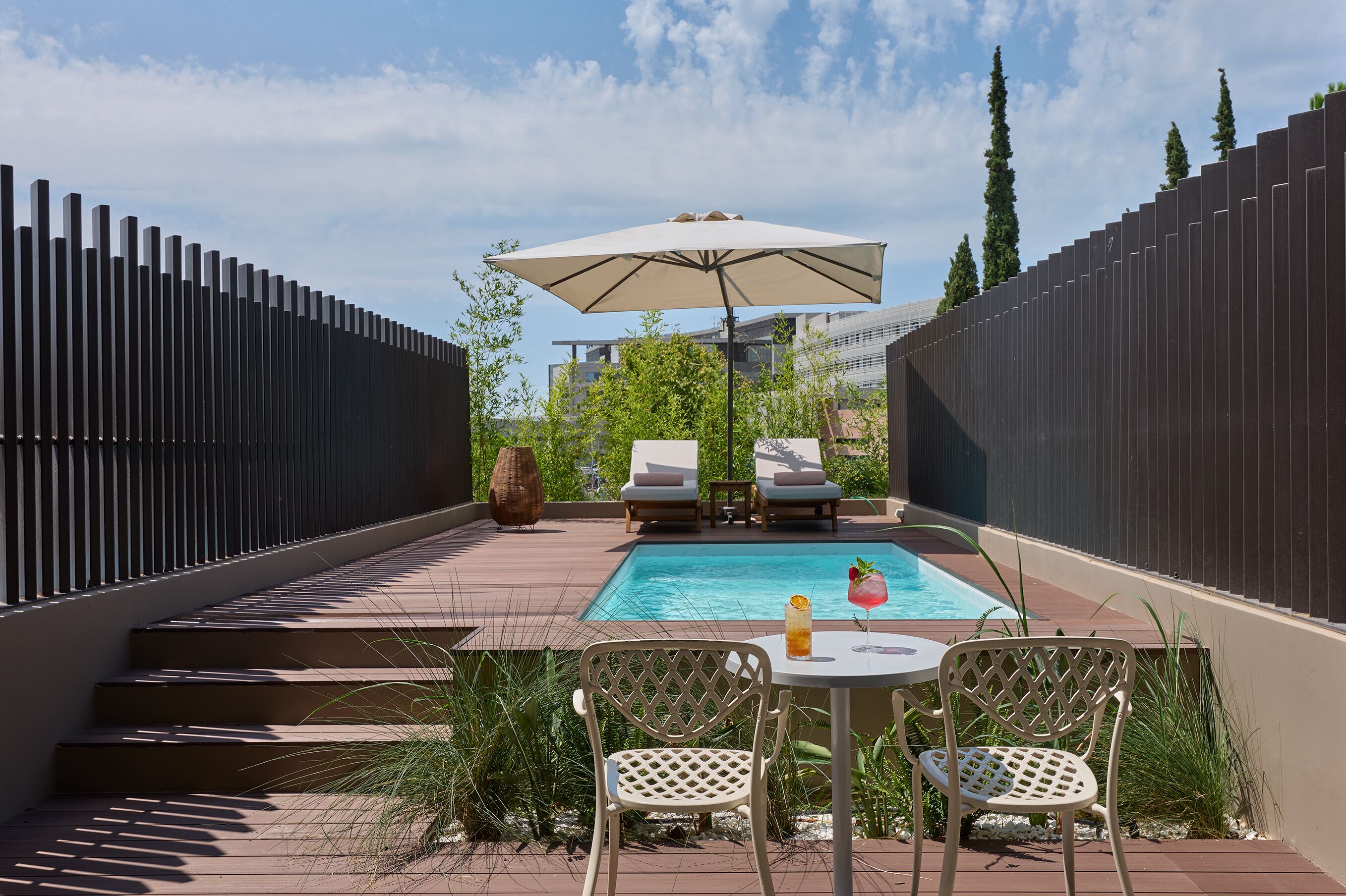 Un espace piscine comprenant une table et des chaises, un fauteuil de relaxation et un parasol.