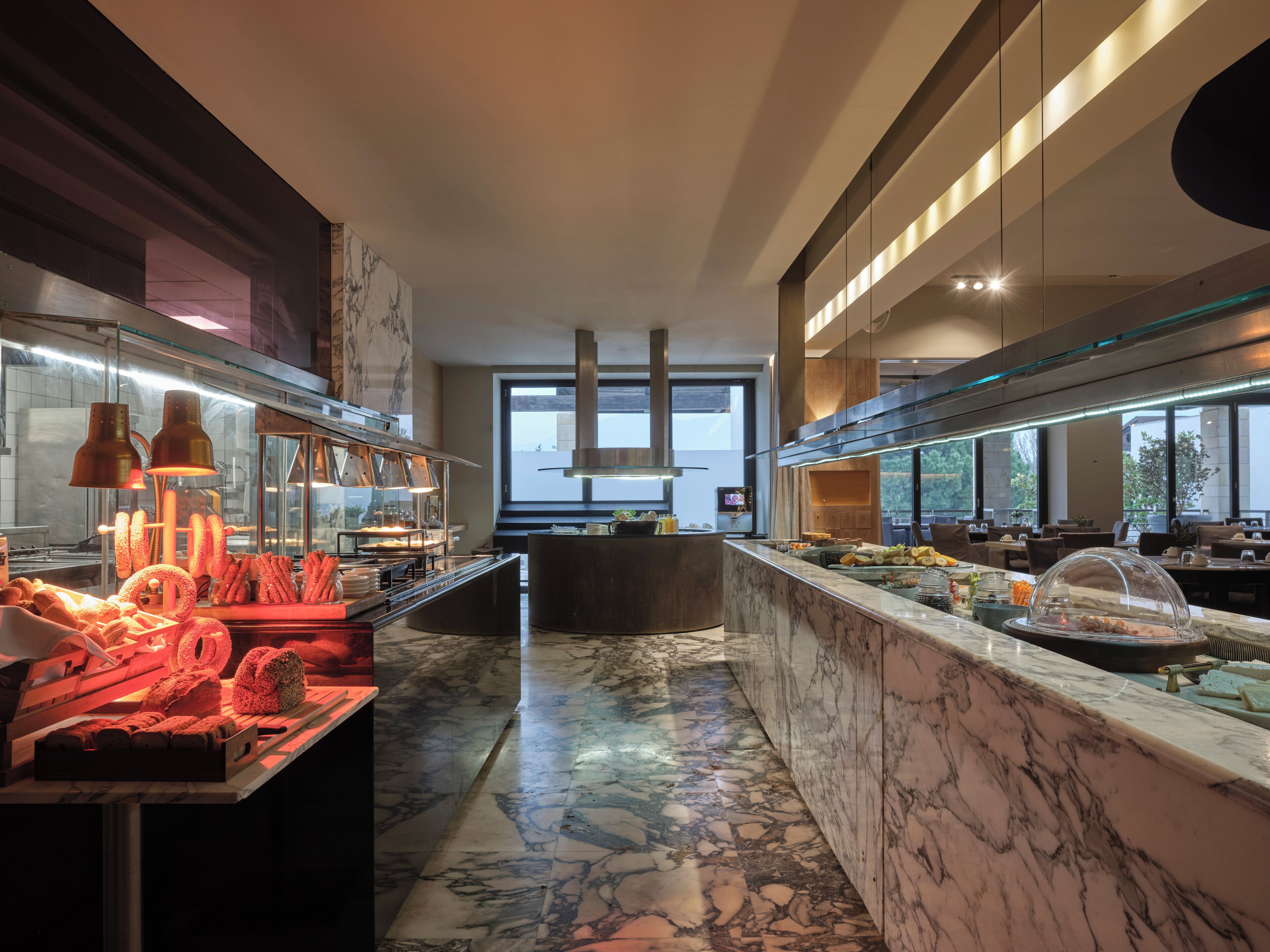 Una cocina moderna con encimeras de mármol, electrodomésticos de acero inoxidable y una isla central con cubierta de vidrio.