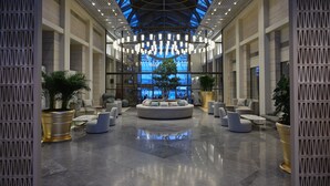 A spacious lobby with a central seating area, large potted plants, and a high ceiling with skylights. - September Hotel Thessaloniki (Pylaia-Chortiatis)