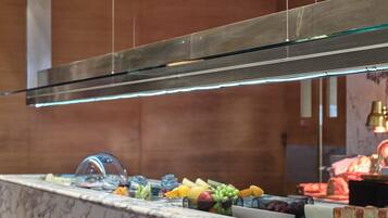A marble countertop with a glass-top display case, a selection of fruits, and a slice of cake on a white plate.