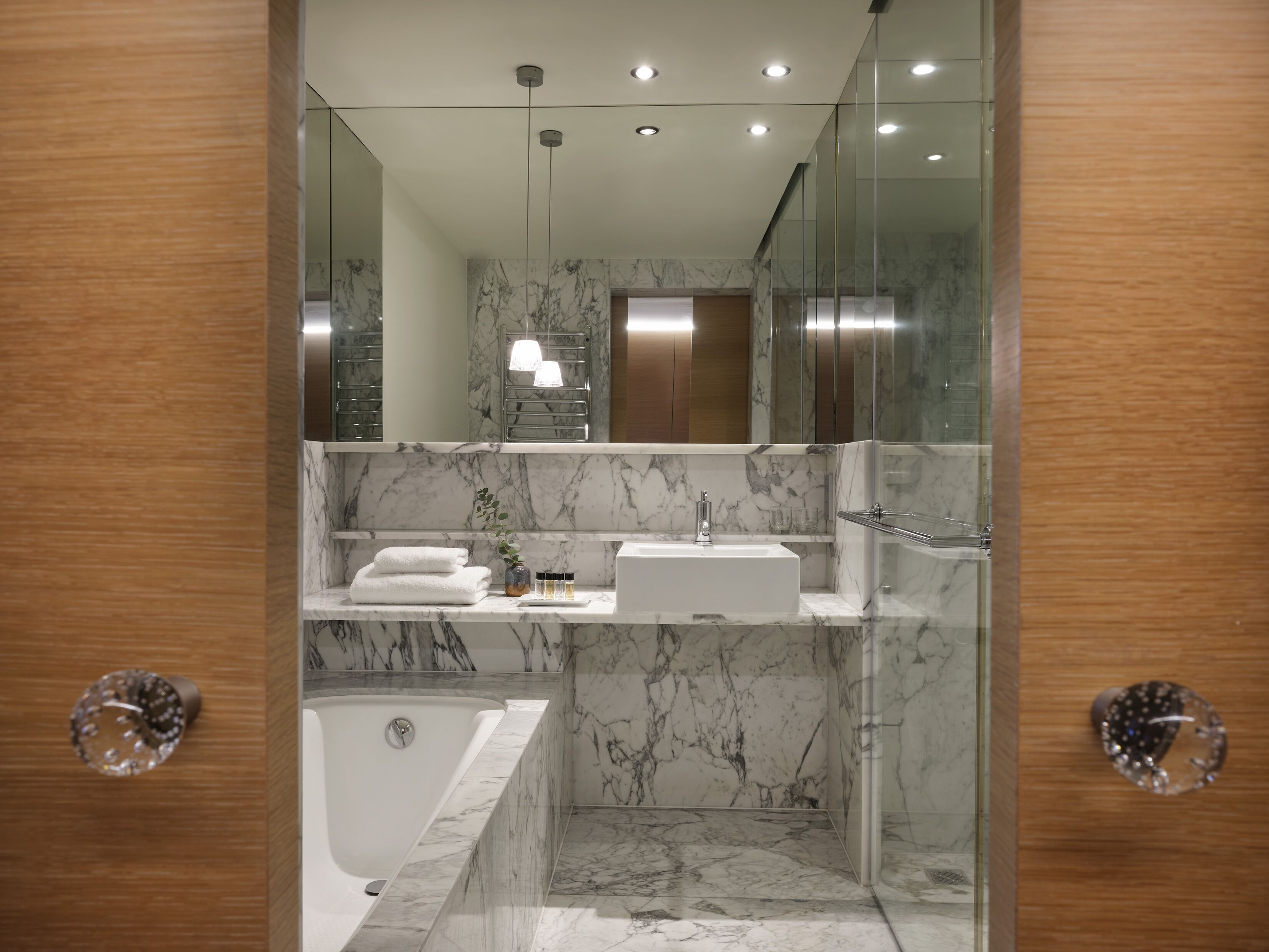 Ein modernes Badezimmer mit Marmorwaschtisch, Badewanne und Duschkabine aus Glas.