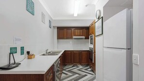 Een moderne keuken met houten kastjes, een wit aanrechtblad en een inbouw vaatwasser.