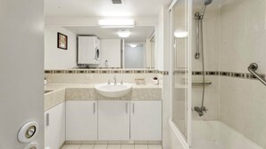 Un baño moderno con lavamanos, espejo y ducha.