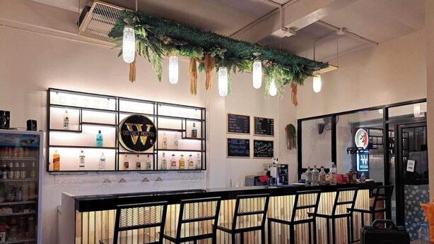 A bar area with a counter, bar stools, and a refrigerated display case. - Butlers WDH (Bangkok)