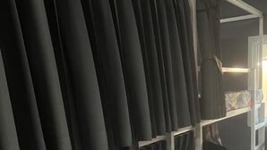 A room with a white bed, a black curtain, and a white shelf with a mirror. - Butlers WDH (Bangkok)