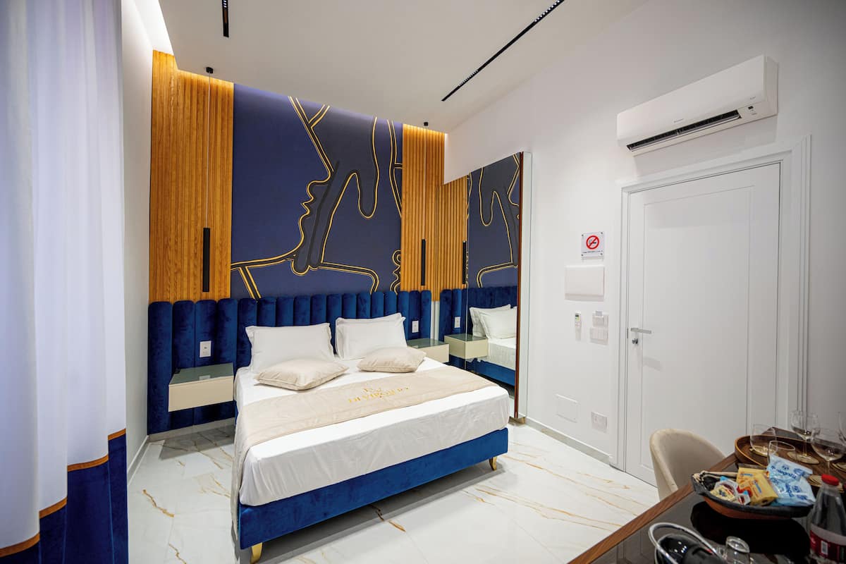 Une chambre moderne avec un grand lit, une tête de lit en bois et une porte blanche.