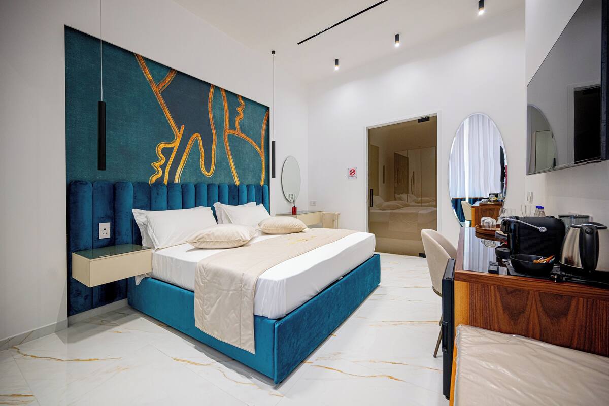 Une chambre d’hôtel moderne avec un grand lit, un bureau doté d’une bouilloire et un miroir.