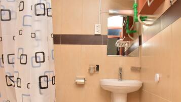 Et badeværelse med toilet, håndvask og badeforhæng.