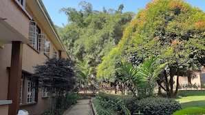 Un sendero empedrado que lleva a un edificio con varias ventanas y un contenedor de basura.