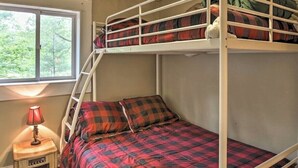 Une chambre avec un lit superposé, une fenêtre, une lampe et un haut-parleur.