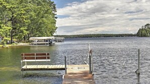 Une jetée en bois s’étendant sur un lac paisible, avec un banc à son extrémité.