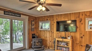 L’intérieur chaleureux de ce chalet est agrémenté de boiseries, d’un ventilateur de plafond, d’un téléviseur, d’une bibliothèque et d’une porte-fenêtre coulissante qui donne sur une terrasse.