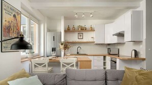 A modern kitchen with white cabinets, a wooden countertop, and a dining area with a white table and chairs. - Cozy Apartment | 2 Balconies | Work Space (Wrocław)