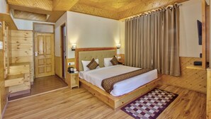 Une chambre à coucher aux murs lambrissés, avec un grand lit, une table de chevet, une lampe fixée au mur et un tapis à carreaux.