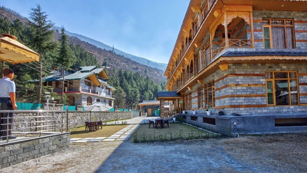 Un bâtiment traditionnel à plusieurs étages, doté de balcons, d’une façade en pierre et d’une cour pavée avec des espaces de repos en plein air.