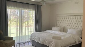 A bedroom with a large bed, a ceiling fan, and a view through the window. - 14 on Carnarvon (Bulawayo)