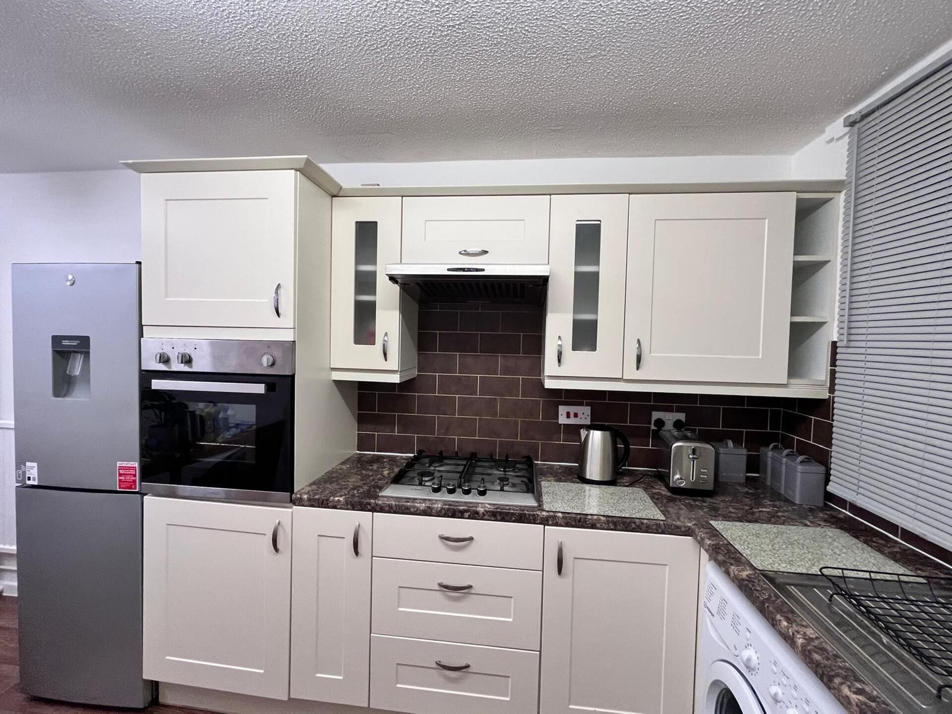 A compact kitchen with a refrigerator, oven, microwave, stove, and a washing machine.