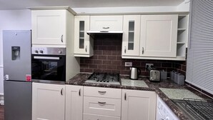 A compact kitchen with a refrigerator, oven, microwave, stove, and a washing machine. - Hive Stays Close to Abbeywood Free Parking Wifi (Erith)