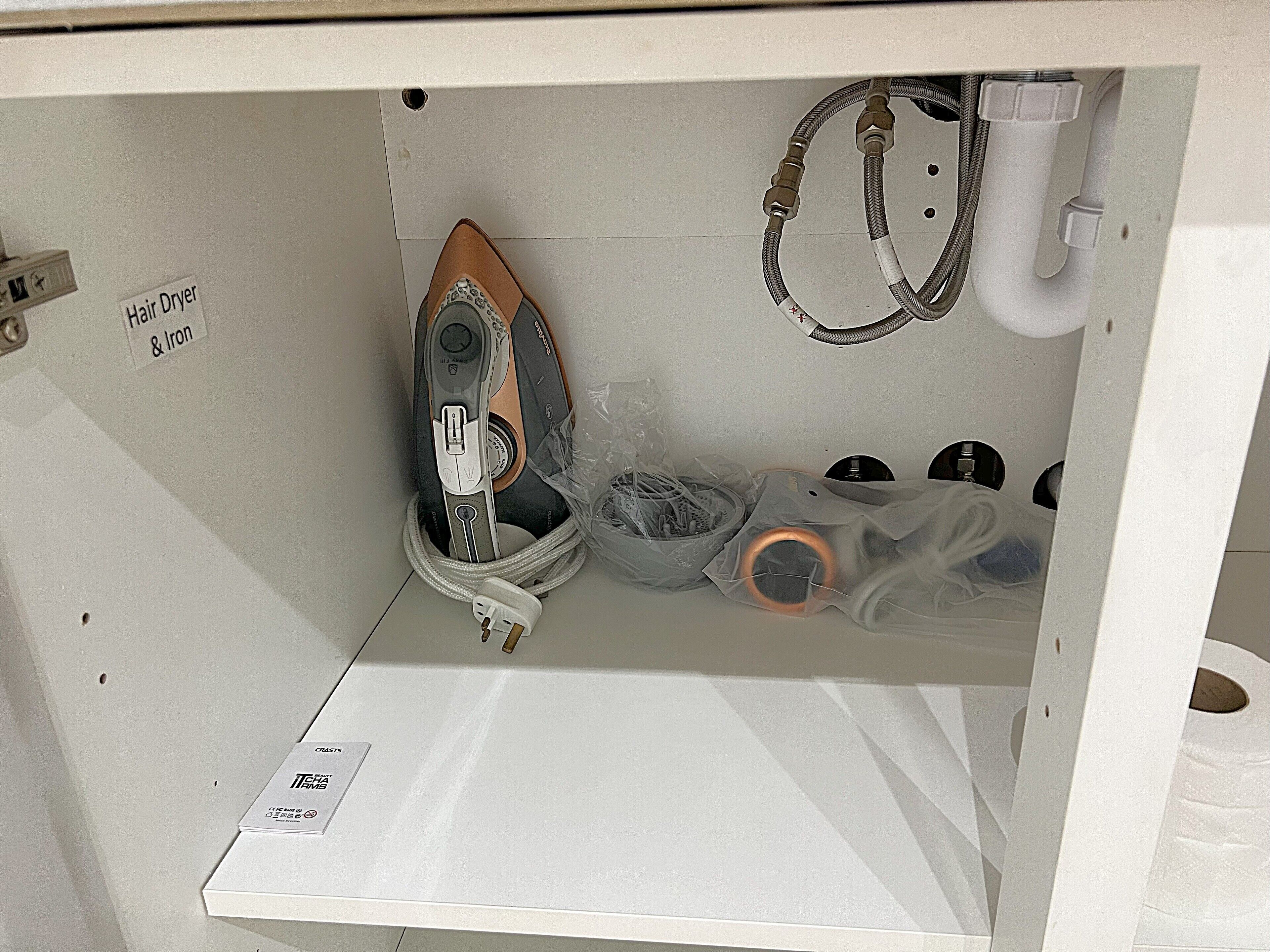 A hair dryer and iron on a white shelf, with a label indicating "Hair Dryer & Iron".
