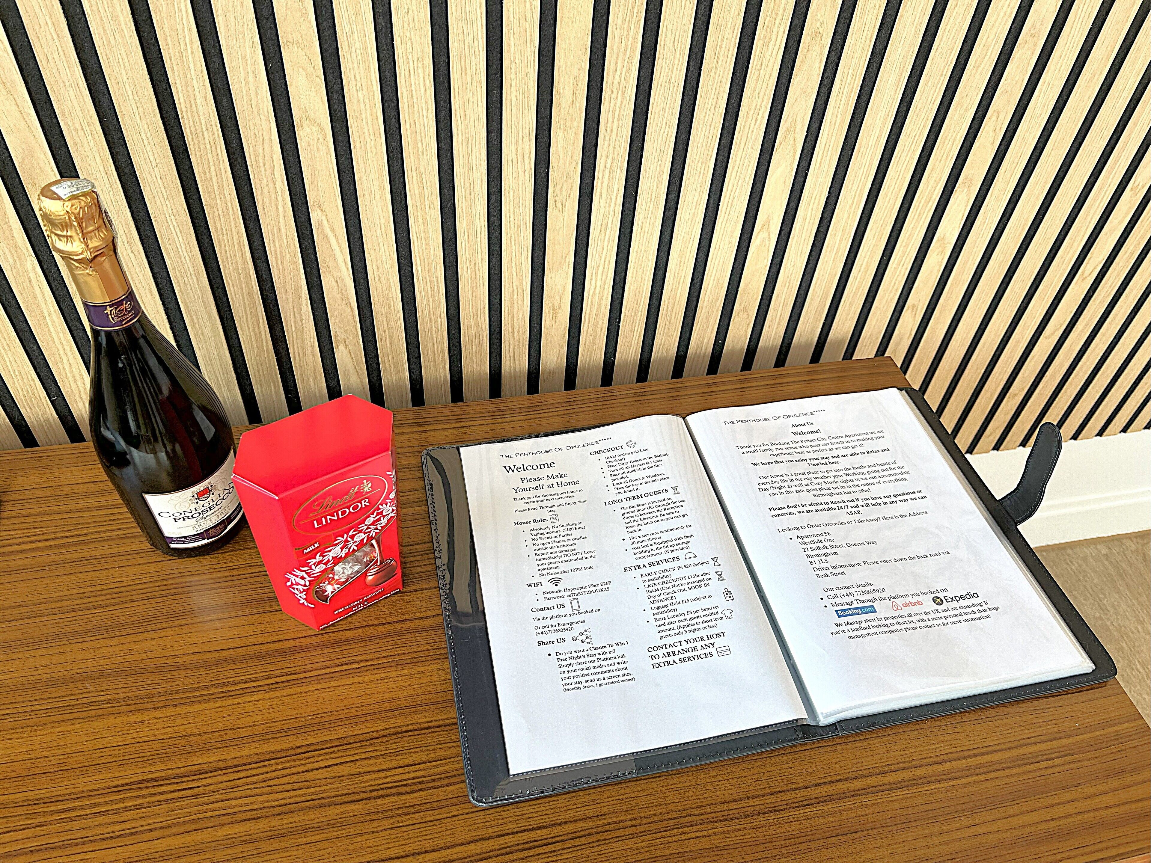 A wooden table with a bottle of wine, a red box, and an open menu.