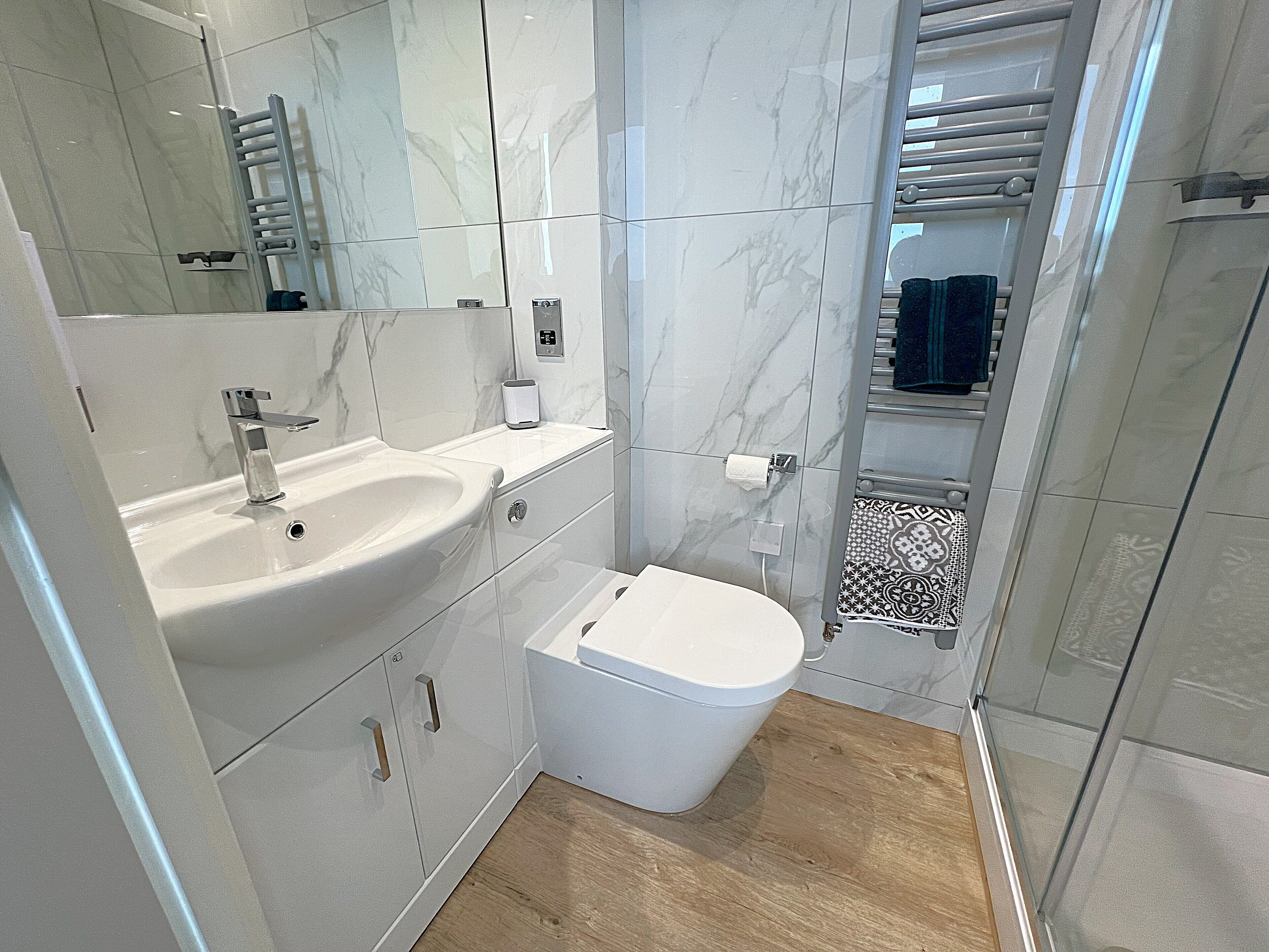 A modern bathroom with a marble sink, a toilet, and a shower area.