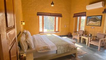 Um quarto com cama, ventilador de teto, janela, cadeira e mesa.