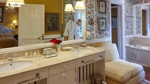 Ein Badezimmer mit doppeltem Waschbecken, einem großen Spiegel und blumigem Wandpapier.