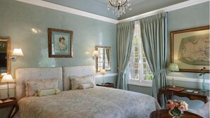 Ein geräumiges Schlafzimmer mit einem großen Bett, einer Kristallleuchter, einem Schreibtisch mit Blumen und einem Sessel.