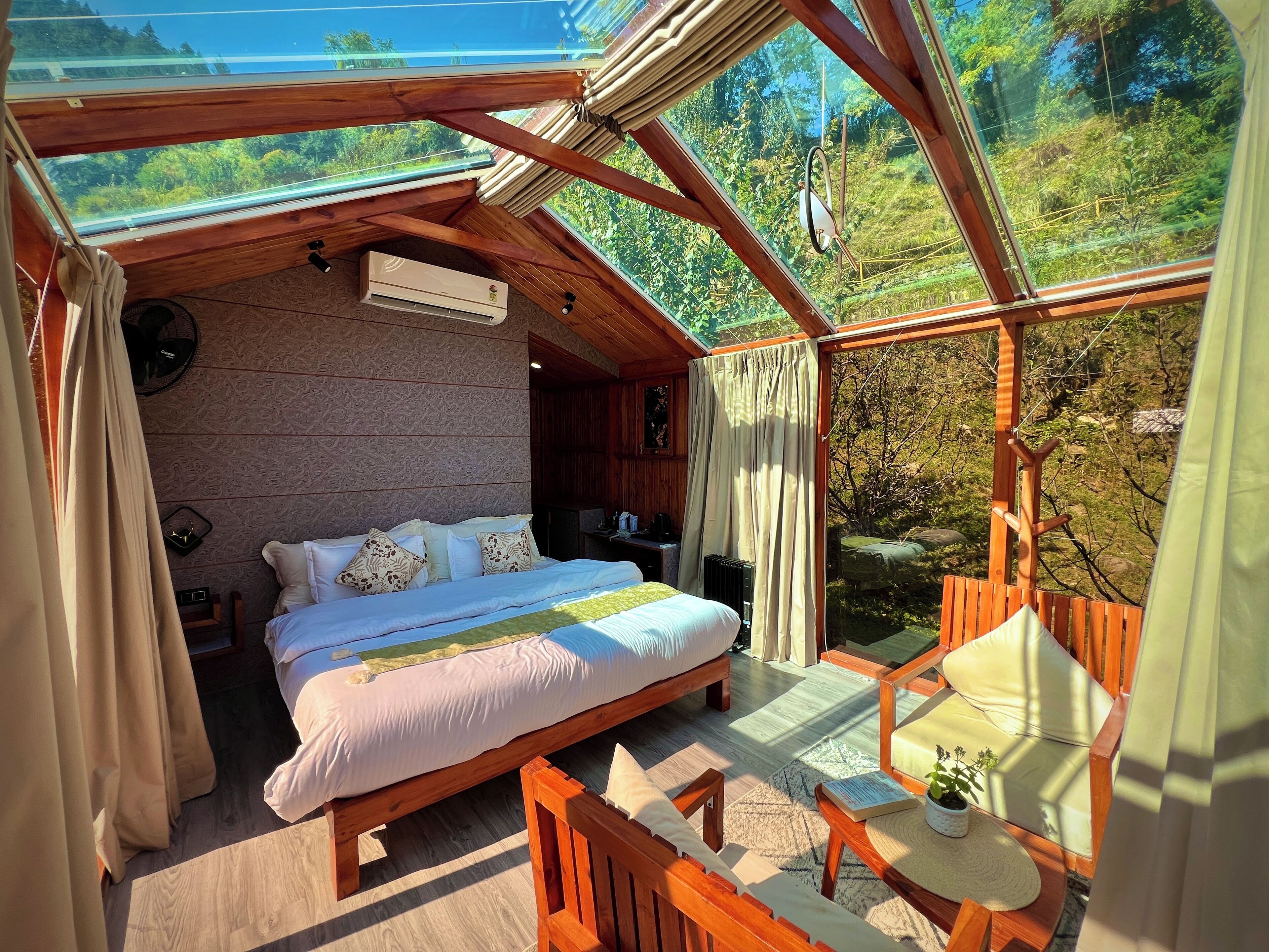 Ein gemütliches Schlafzimmer mit einem großen Bett, Holzbalkendecke und Blick auf üppiges Grün.
