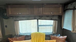 En sort lædersofa med et gult plaide og mønstrede puder i en autocamper.