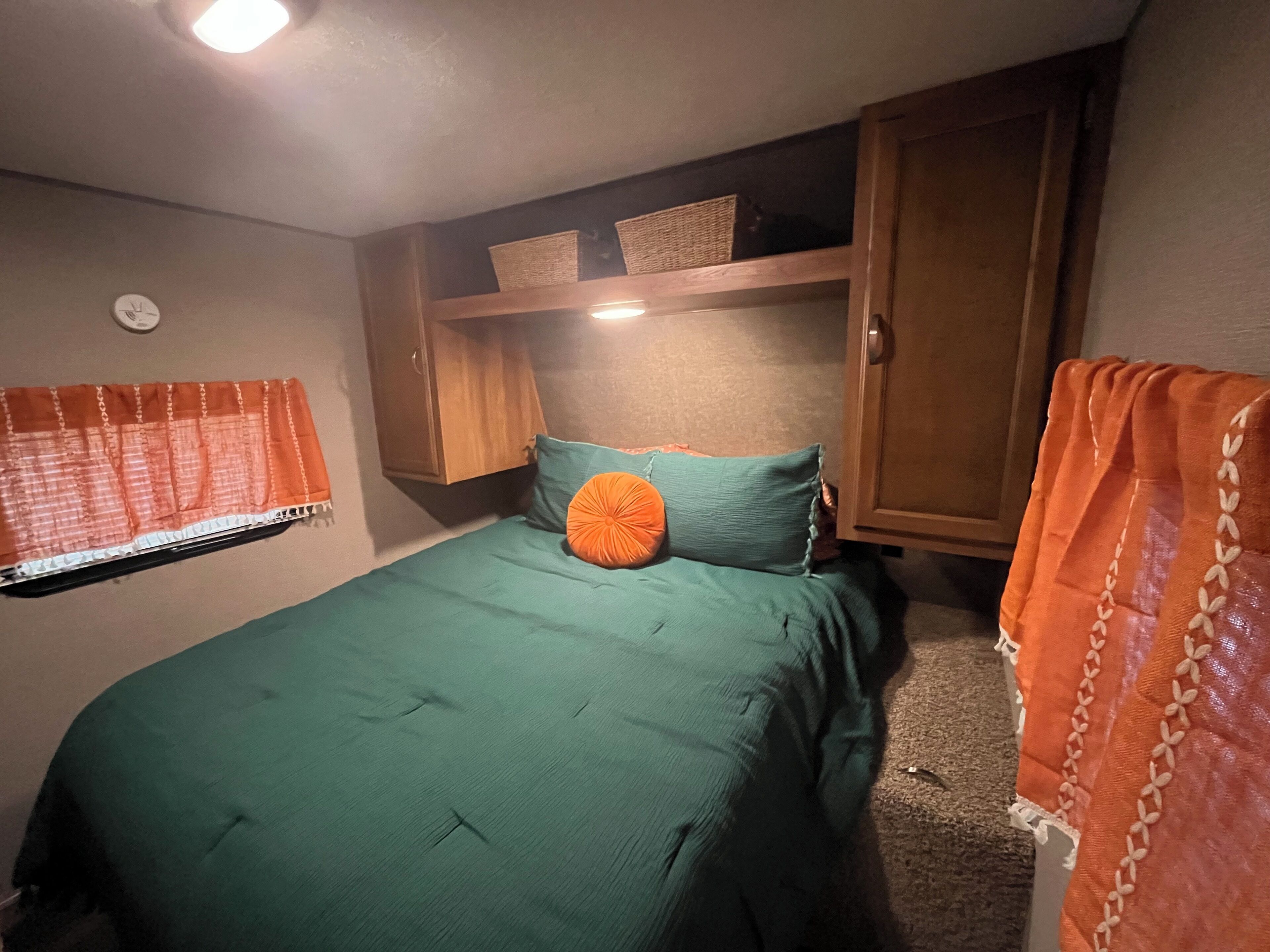 A bedroom with a bed, a nightstand, a wardrobe, and a window with curtains.