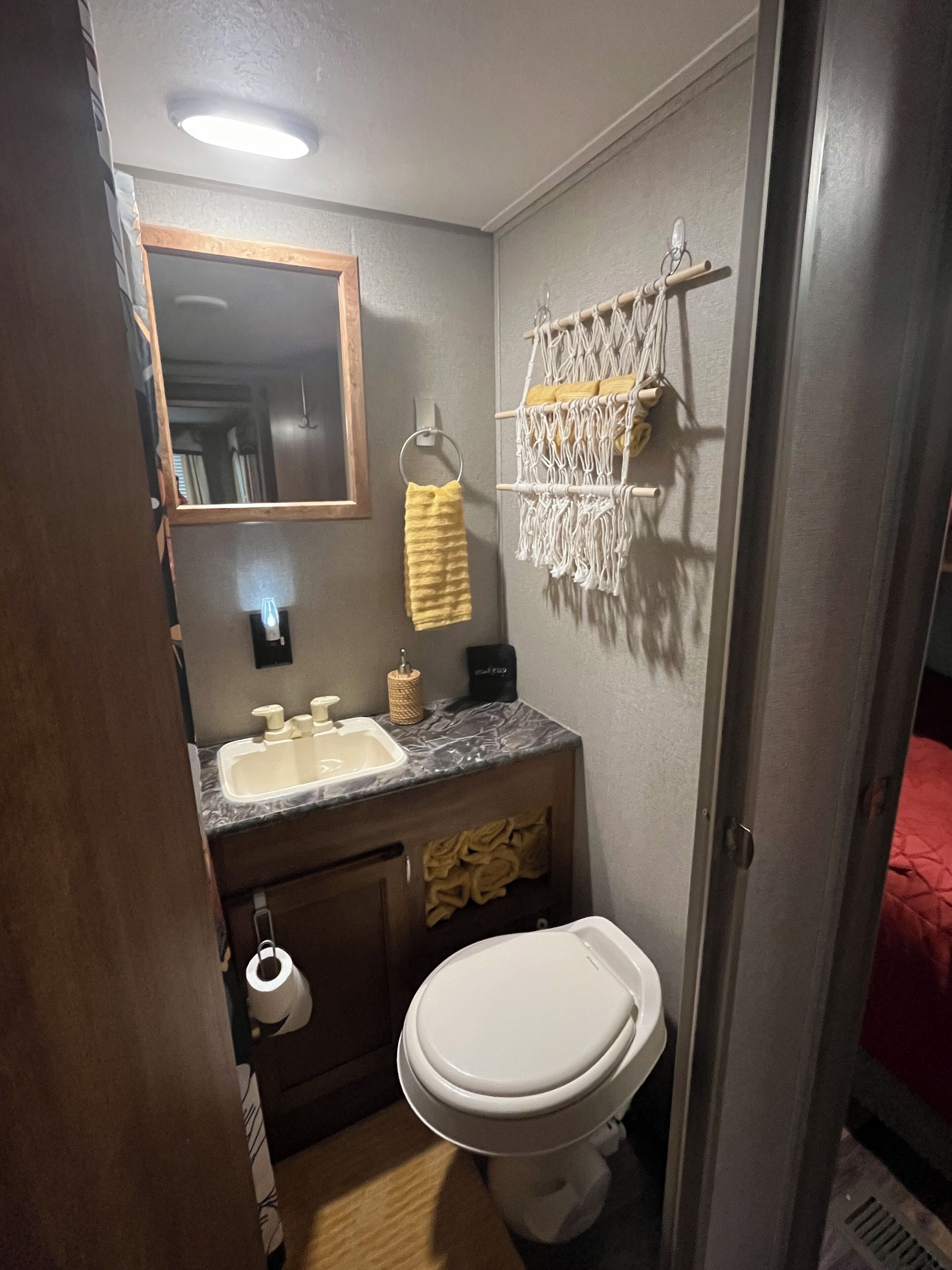 Een kleine badkamer met een wastafel, spiegel, toilet en handdoekhouder.