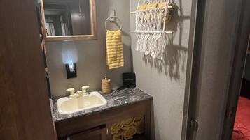 Een kleine badkamer met een wastafel, spiegel, toilet en handdoekhouder.