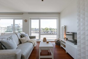 Relax in this stylish living room with a large sofa, flat-screen TV, and city views.