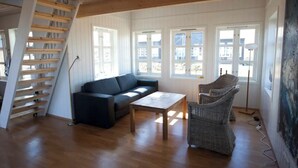 A spacious living room with a wooden staircase, a sofa, a coffee table, and wicker chairs. - Day Dream Hellnar (Hellnar)