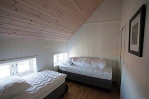 Une chambre avec deux lits, un plafond en bois et de grandes fenêtres.