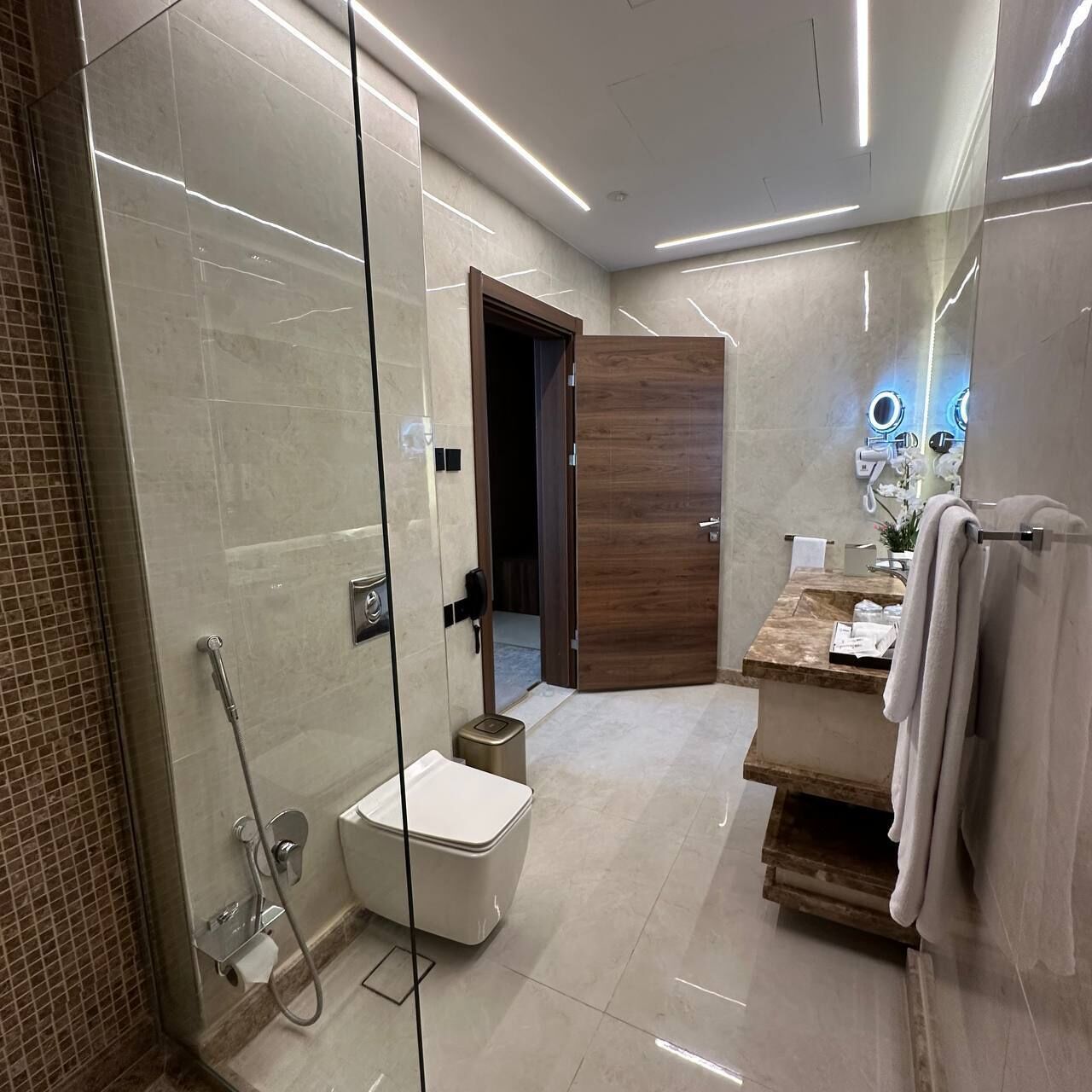 Un baño moderno con ducha envuelta en vidrio, inodoro y tocador con espejo.