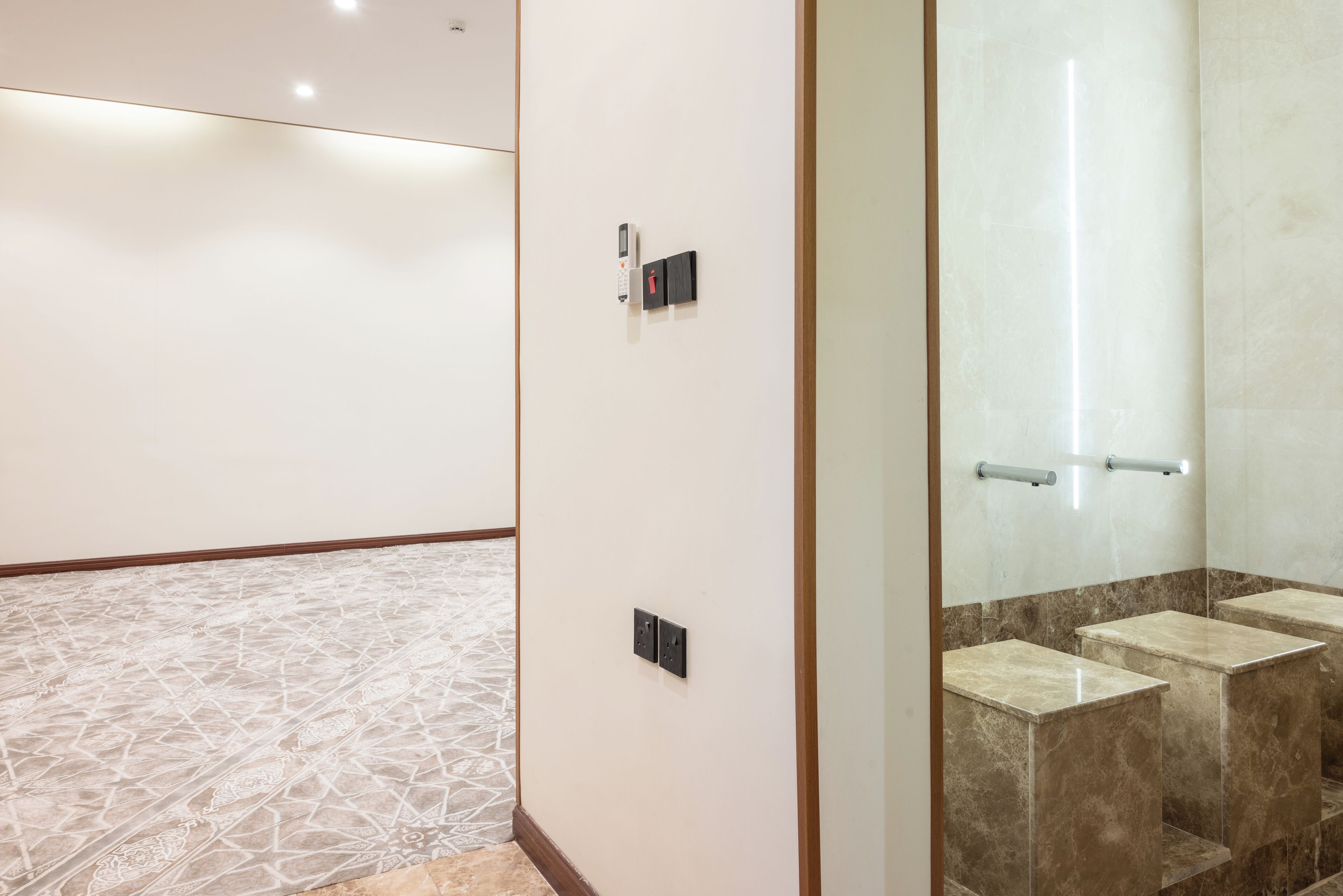 Ein Hotelkorridor mit einem gemusterten Boden, einem an der Wand montierten Telefon und einer Toilette mit Marmorstufen.