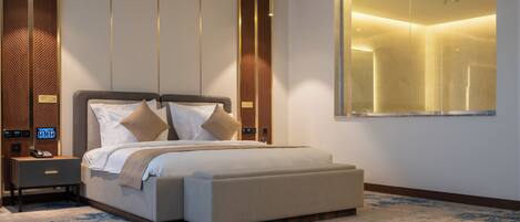 A modern hotel room with a large bed, bedside tables, a built-in TV, and a large window.