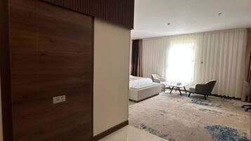 Una habitación de hotel con un armario grande, una cama, un sofá, una silla y una mesita.