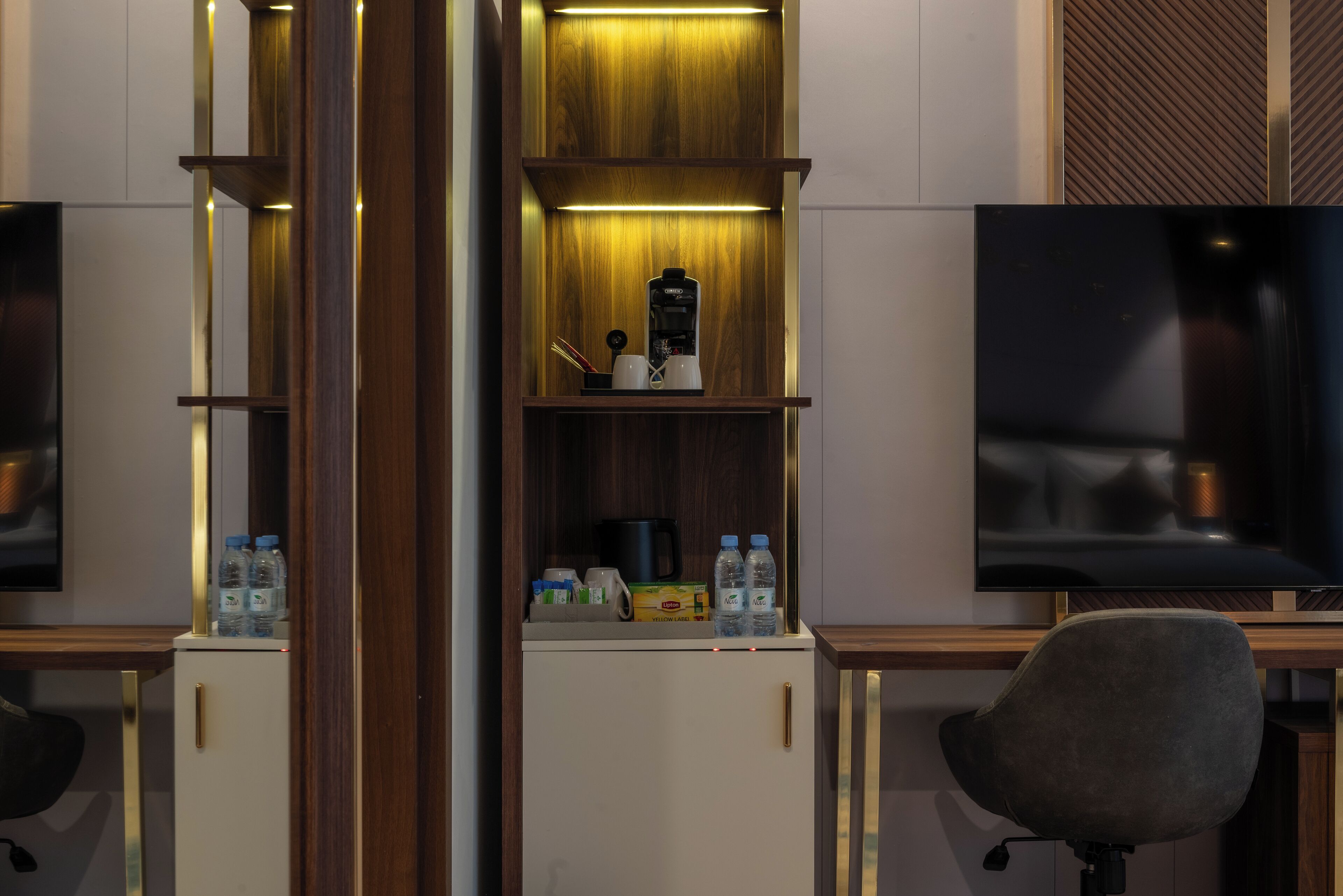 A modern hotel room with a wooden cabinet, a coffee maker, and a TV on a wooden stand.