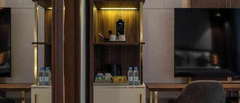 A modern hotel room with a wooden cabinet, a coffee maker, and a TV on a wooden stand.