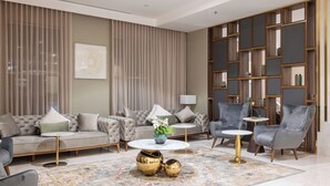 Un soggiorno moderno con divano, poltrone, tavolino e un tappeto decorativo.