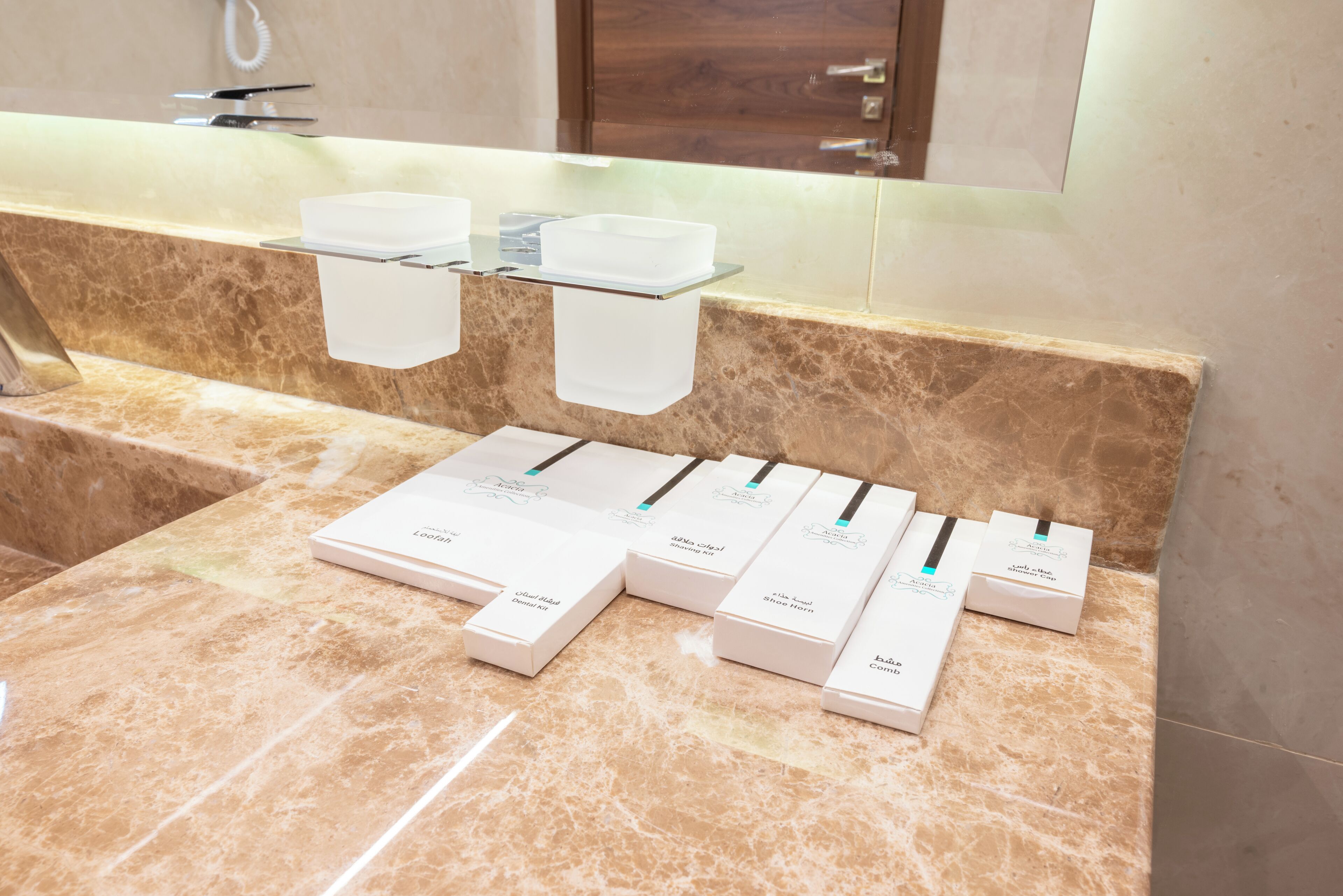 A bathroom with a marble countertop, a glass soap dish, and several white boxes labeled with product names.