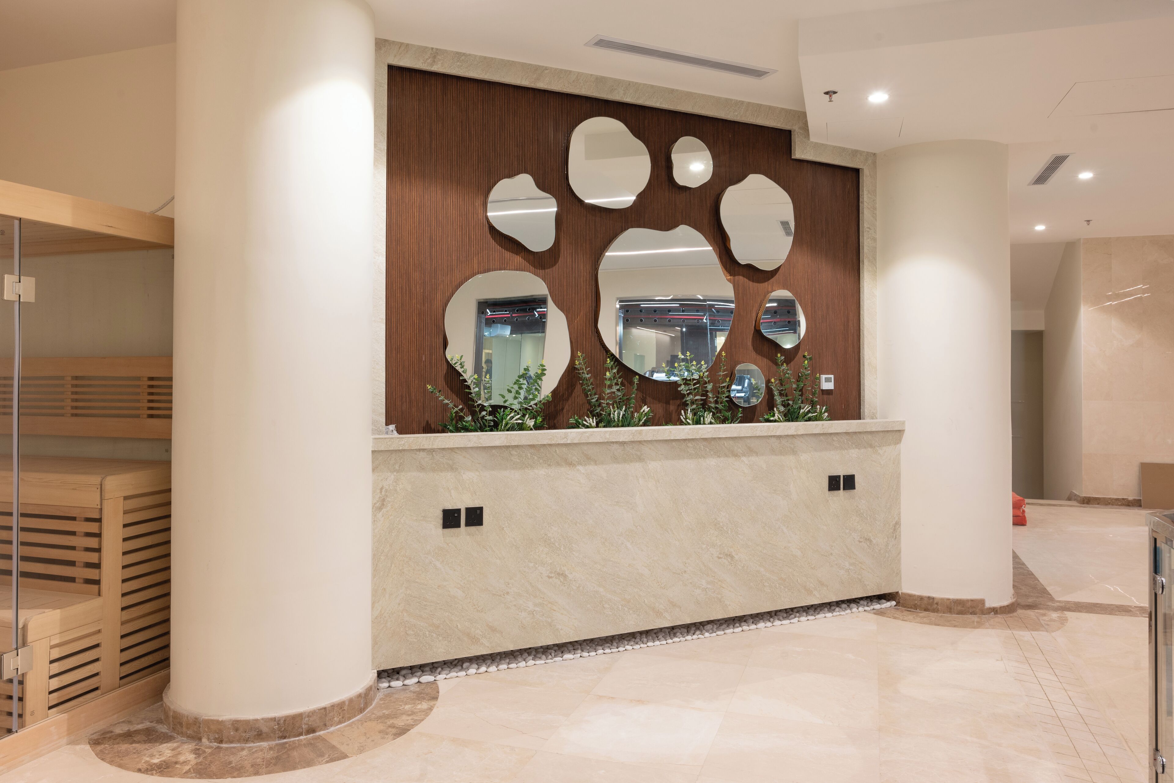 A reception area with a wooden panel wall, multiple mirrors, and a marble counter.