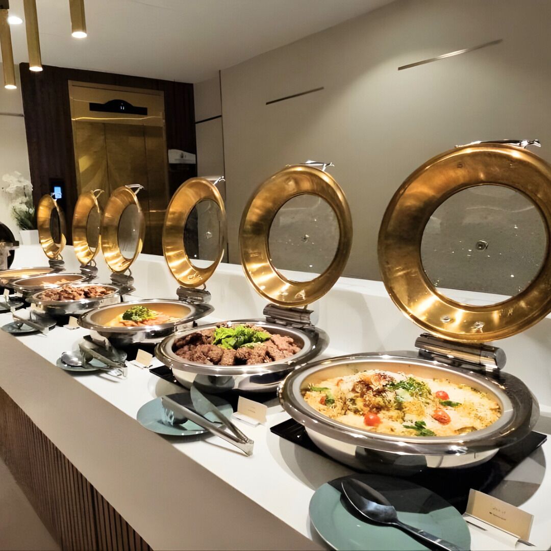A buffet with multiple round serving dishes, each with a golden rim, arranged on a counter.