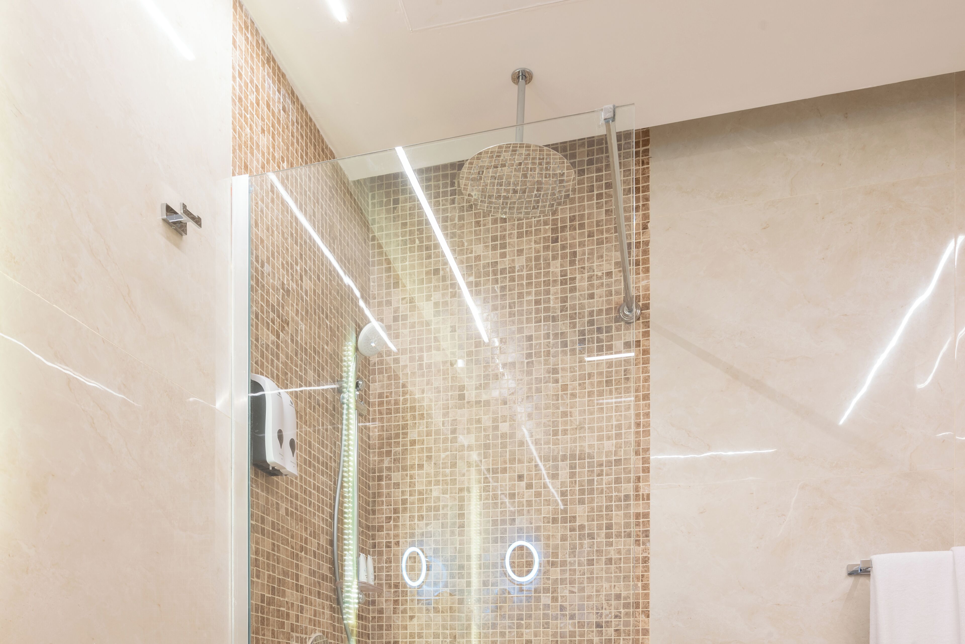 A modern bathroom with a glass-enclosed shower, tiled walls, and a visible towel rack.